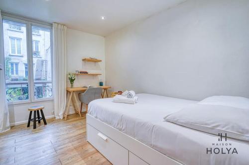 une chambre blanche avec un lit et un bureau dans l'établissement Le Studieux - À Oberkampf - 82B, à Paris