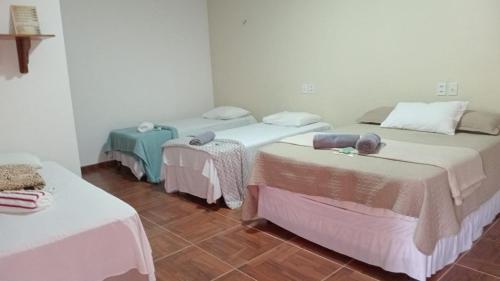 a room with three beds and two tables at Pousada Recanto Sapoti in Barreirinhas