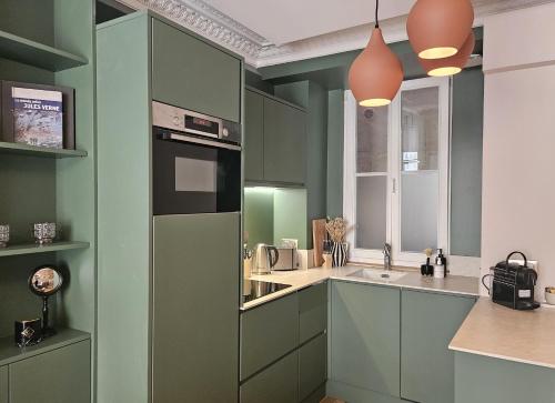 une cuisine avec des armoires vertes et un évier dans l'établissement Chic Apartment By Capucine - Grands Magasins, à Paris