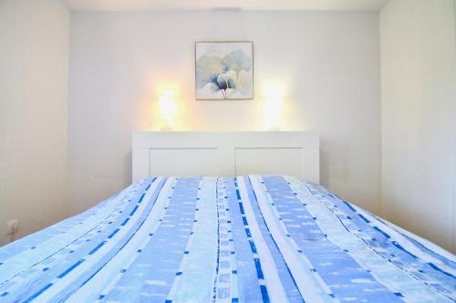 - une chambre blanche dotée d'un lit avec des draps bleus dans l'établissement CAPRI Appartement confort bord de mer, à Saint-Mandrier-sur-Mer