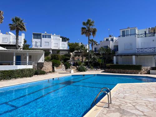ein Pool vor einigen weißen Gebäuden in der Unterkunft Sunset Deluxe Villa and Studios in Paphos City