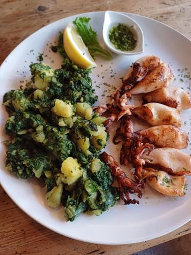 a plate of food with shrimp and broccoli on a table at Mala Taverna in Kalwang