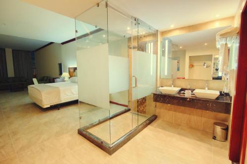 a bathroom with a glass shower and a bed at Ramada by Wyndham Princess Georgetown in Georgetown
