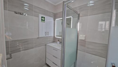 een witte badkamer met douche en wastafel bij Casa Belice in Vila Real de Santo António