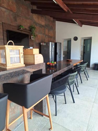 a kitchen with a long counter with chairs and a table at Max Suíte in Capitólio
