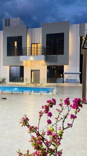 a large building with a swimming pool with purple flowers at بيت الشرقية in Mazra‘at Shuway‘ī