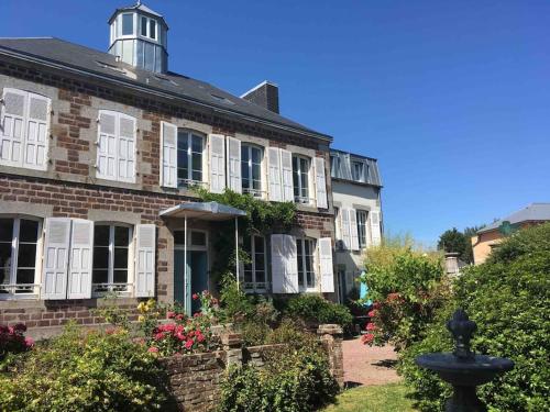 une maison en briques avec une fontaine devant elle dans l'établissement Bonheur and Company, à Bréhal