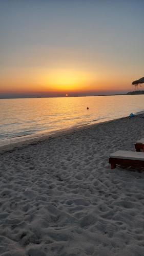a beach with a bench and the ocean at sunset at Olympus Sea View Apartment. in Nea Kalikratia
