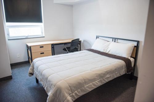 a bedroom with a bed and a desk and a window at Residence & Conference Centre - North Bay in North Bay
