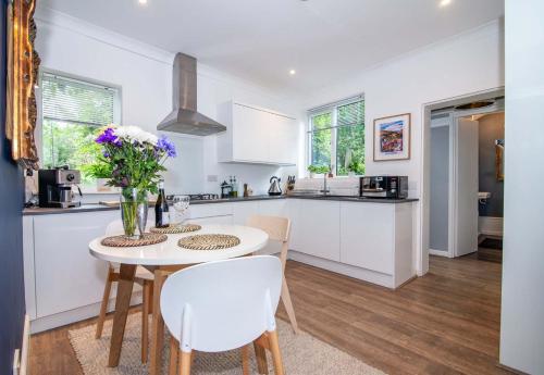 Una cocina con gabinetes blancos y una mesa y sillas. en Host & Stay - Terrace House on Canal, en Worcester
