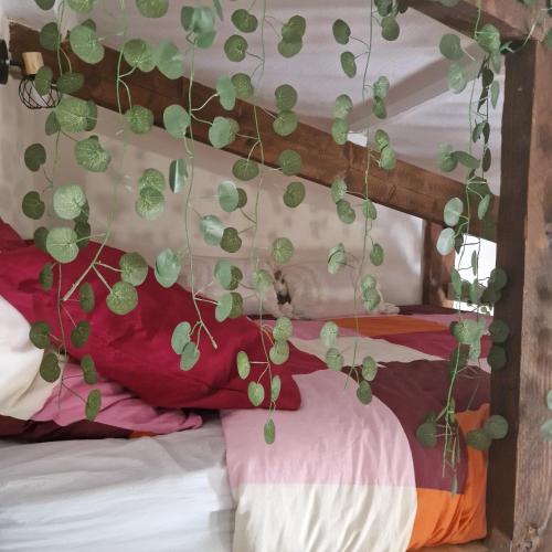 un lit avec une bande de plantes vertes accrochées à celui-ci dans l'établissement Paris Villette by metro 7, France Stadium, break moment studio, à Aubervilliers