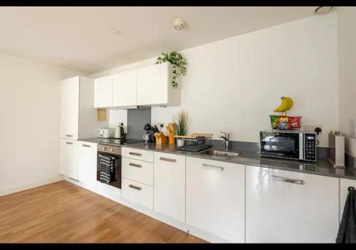 a kitchen with white cabinets and a black microwave at The Nest of Forest Hill in Forest Hill