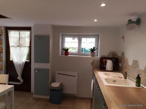 eine Küche mit einer Theke, einem Waschbecken und 2 Fenstern in der Unterkunft charmante maisonnette au calme in Montélimar