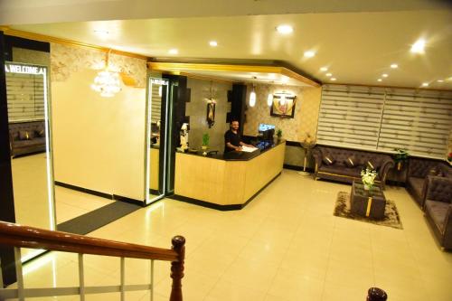 a man standing at a counter in a lobby at Rajalakshmi Comforts Mysuru in Mysore