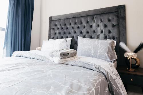 a bedroom with a white bed with a gray headboard at Exquisite Getaway - Luxury Apartment in Sandown
