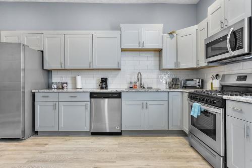 a kitchen with white cabinets and stainless steel appliances at Modern Midtown 1B Apartment King Bed and Smart TVs in Omaha