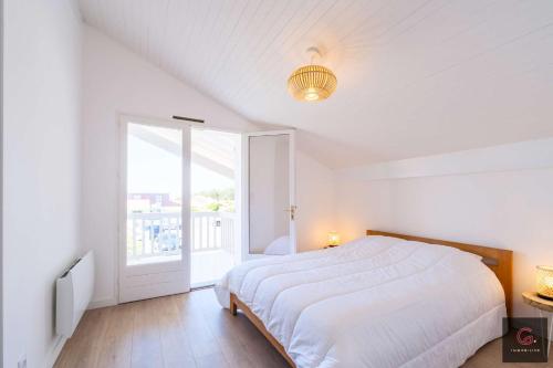 une chambre blanche avec un lit et une grande fenêtre dans l'établissement Biscarrosse Plage Villa avec piscine pour 12 personnes, à Biscarrosse-Plage