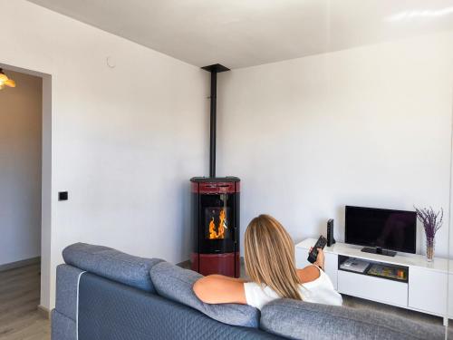 a woman sitting on a couch in a living room with a fireplace at Apartamento rural en el Berguedà "Lluis & Antonia" A Ac in Sant Jordi de Cercs