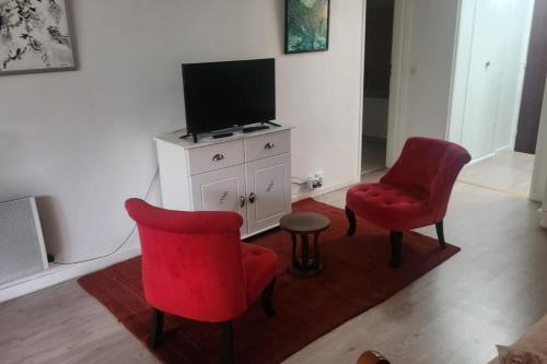 sala de estar con 2 sillas rojas y TV en Getaway for two cosy apartment with balcony, en Trouville-sur-Mer