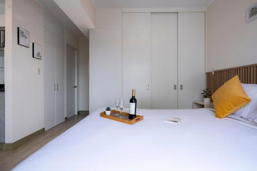 a bedroom with white walls and a bed with a bottle of wine at Connect Studios by Vibrant in Lima