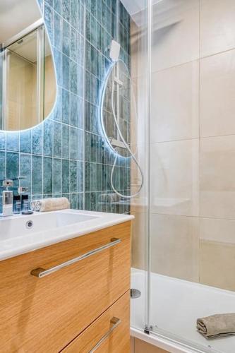 une salle de bain avec une douche, un lavabo et un miroir dans l'établissement Appartement Luxueux Cosy - Paris Expo, à Vanves