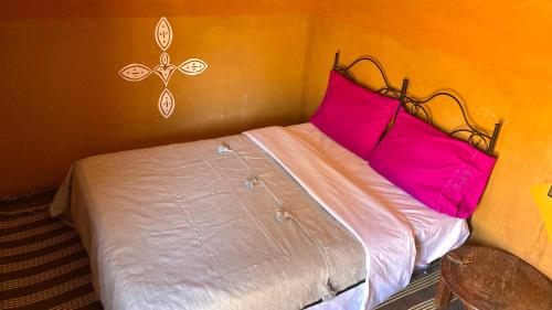 a bed with pink pillows in a room at Sahara Camp Light in Mhamid