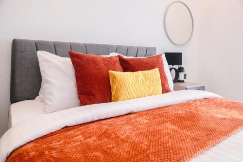a bed with orange and white pillows and a mirror at Luxury Studios by Home in Mpehuasem