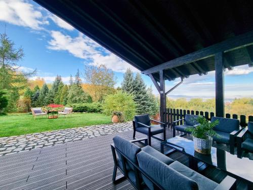 a wooden deck with blue chairs and a patio at Sporthaus Sosnówka - Deluxe Villa & Garden in Sosnówka