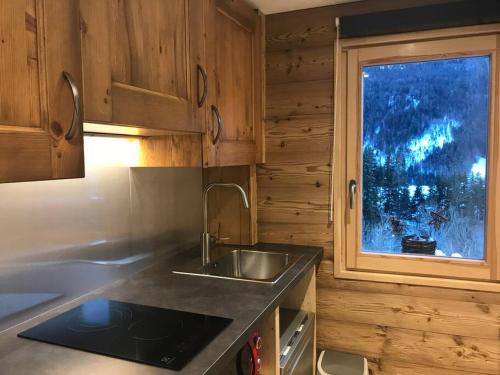 une cuisine avec un évier et une fenêtre dans l'établissement Le Nid du Farzy, au cœur des Aravis, au Grand-Bornand