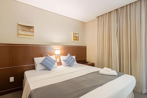 a bedroom with a large white bed with blue pillows at Flats Osasco Trade Center in Osasco
