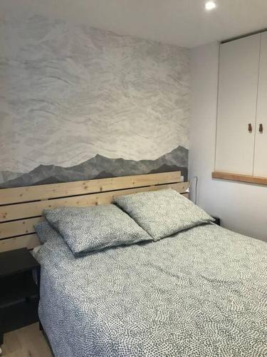une chambre avec un lit avec un tableau sur le mur dans l'établissement Le Nid du Farzy, au cœur des Aravis, au Grand-Bornand