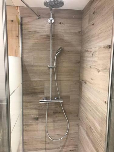 une douche dans une salle de bain avec un mur en bois dans l'établissement Le Nid du Farzy, au cœur des Aravis, au Grand-Bornand