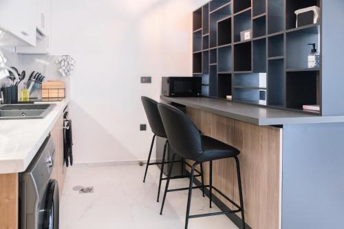 a kitchen with two black chairs at a counter at Luxury Studios by Home in Mpehuasem