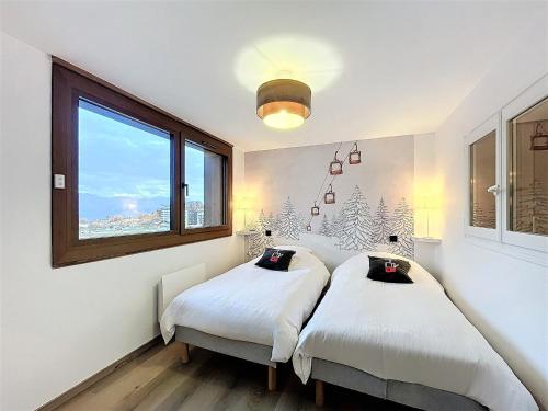 two beds in a room with a window at Appartement rénové, ski aux pieds, centre station, 8 pers, balcon, WiFi - FR-1-267-301 in La Toussuire