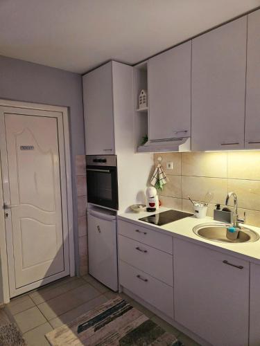 a kitchen with white cabinets and a sink and a door at TIHA VODA 4 in Požarevac