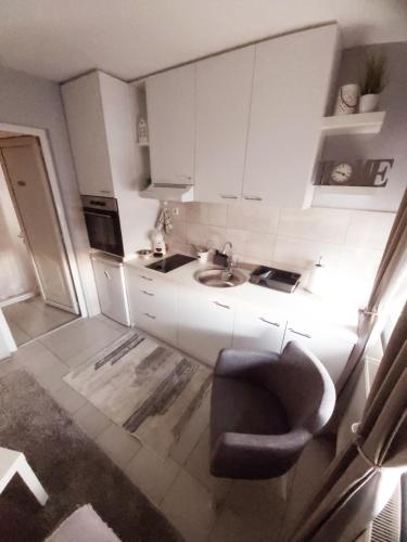 a small white kitchen with a sink and a chair at TIHA VODA 4 in Požarevac