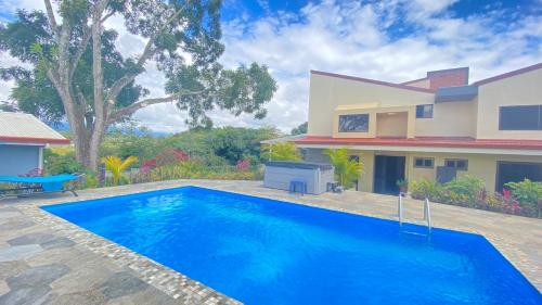 a villa with a swimming pool in front of a house at Casa Marigold -Apartamento Bondad in Alajuela City