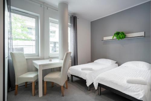 a room with two beds and a table and chairs at Keja Aparts - 03 Gdynia Centrum in Gdynia