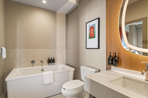 a bathroom with a tub and a toilet and a sink at Hotel Indigo Baton Rouge Downtown by IHG in Baton Rouge
