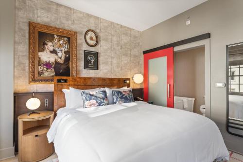 a bedroom with a white bed and a painting on the wall at Hotel Indigo Baton Rouge Downtown by IHG in Baton Rouge