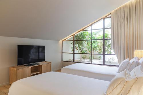 a bedroom with two beds and a large window at Casa da Companhia Hotel & Spa, Vignette Collection by IHG in Porto