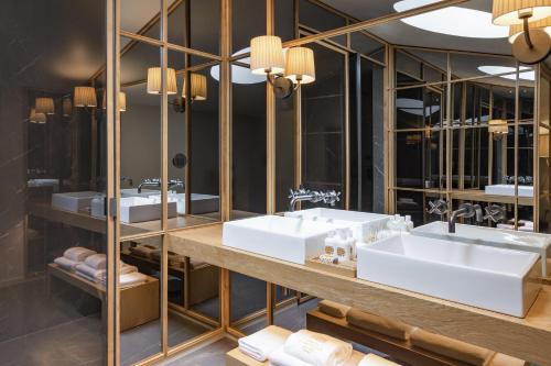 a bathroom with three sinks and mirrors at Casa da Companhia Hotel & Spa, Vignette Collection by IHG in Porto