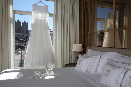 a wedding dress hanging in a bedroom with a window at Casa da Companhia Hotel & Spa, Vignette Collection by IHG in Porto