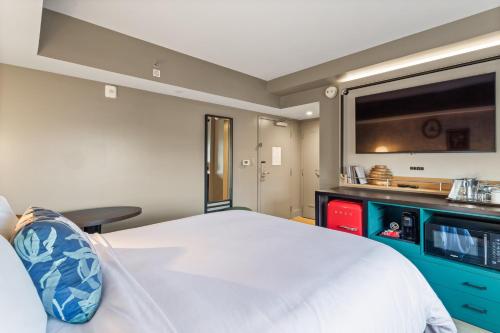 a bedroom with a large white bed and a flat screen tv at Hotel Indigo Baton Rouge Downtown by IHG in Baton Rouge
