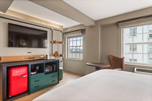 a bedroom with a bed and a tv and a chair at Hotel Indigo Baton Rouge Downtown by IHG in Baton Rouge