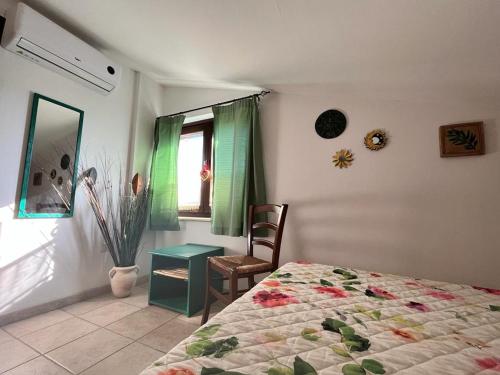 a bedroom with a bed and a chair and a window at A Casa di Amici in Tuscania