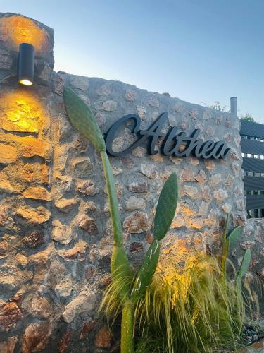 a sign on a stone wall with a plant at Althea Apartments in Kolimbia