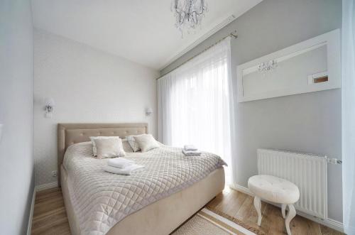 a white bedroom with a bed and a window at Apartament Glamour in Pobierowo