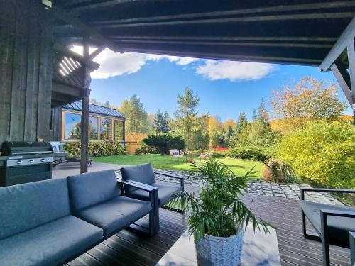 a patio with a couch and a grill at Sporthaus Sosnówka - Deluxe Villa & Garden in Sosnówka