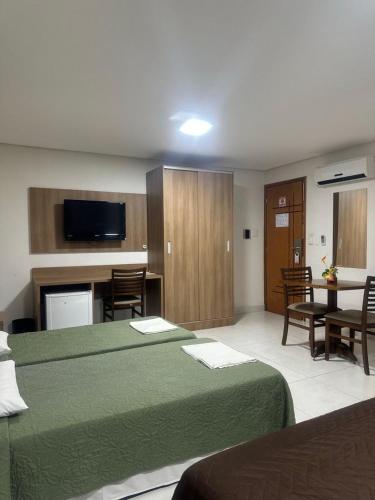 a hotel room with two beds and a table and chairs at Matinada Palace Hotel in Paraguaçu